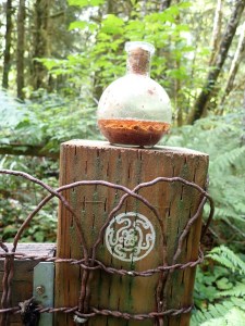 Round bottle containing fluid sits on a fencepost with a circular symbol on it.