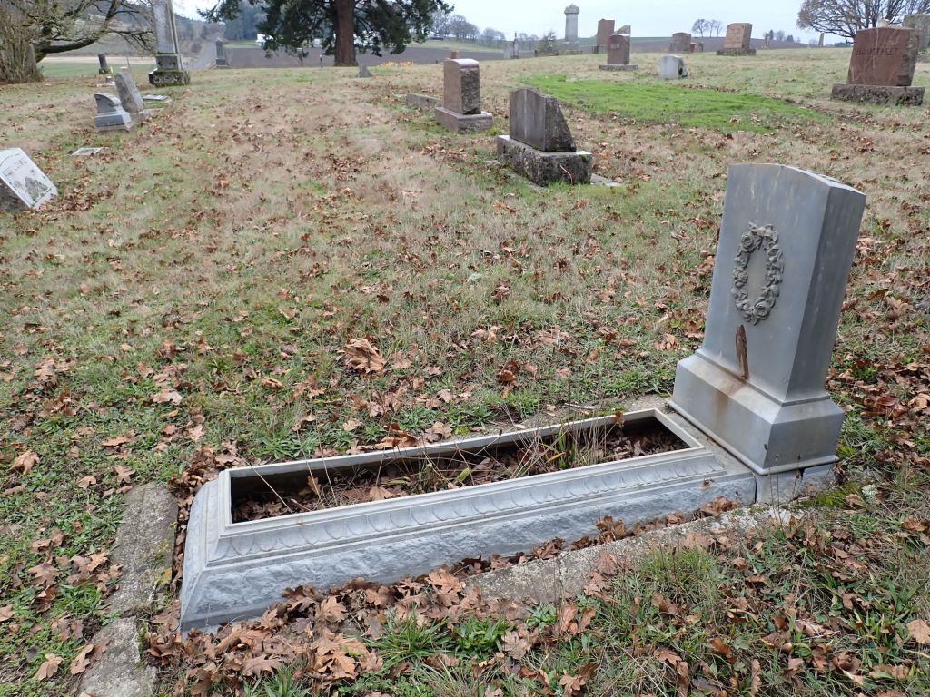 Photo of a tombstone with a long flower bed frame attached